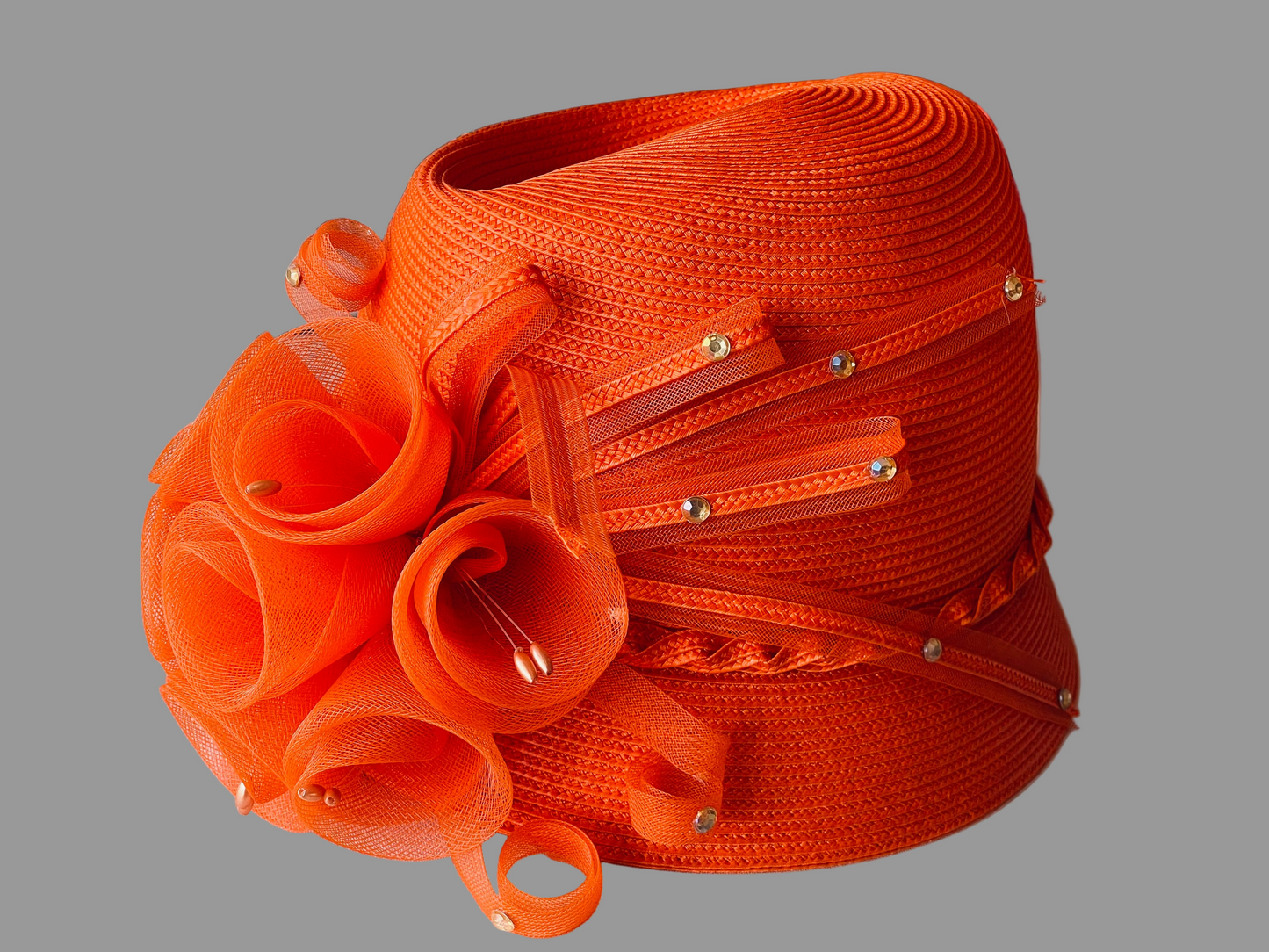 Orange decorative hat with intricate design on a white surface